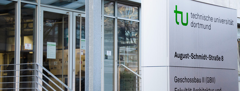 Eingang zum Geschossbau 2, daneben Schild der Fakultät Architektur und Bauingenieurwesen.