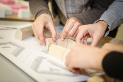 Studierende am Holzmodell Studierende platzieren Holzbausteine ihres Holzmodells.